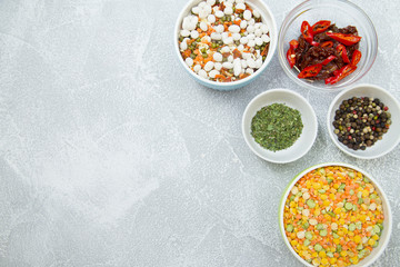 Set of raw ingredients for Italian cooking on stone table background. Black papper, sun dried tomatos, green dry species and beans. Set of healthy food products. Closeup
