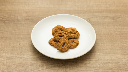 Cookies with a hole, sweet temptation. Dessert on white dish and wooden table.