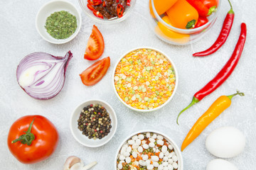 Set of raw ingredients for Italian cooking on stone table background. Sun dried tomatos, red and yellow pappers, garlic, onion, beans, eggs and black papper. Closeup and top view