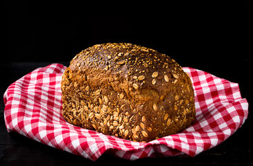 Granary spelt bread on red kitchen towel and black background