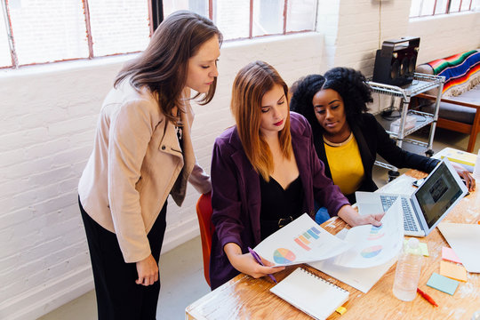 Colleagues in office discussing graphical data on paperwork