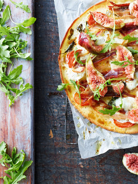 Fresh pizza with rocket leaf and fig, overhead view
