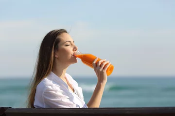 Crédence de cuisine en verre imprimé Jus Femme buvant un jus d& 39 orange sur la plage