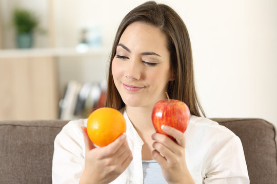 Woman deciding between an orange and apple