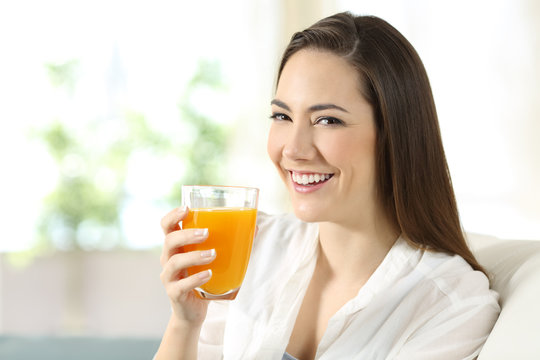 Woman holding a glass of orange juice at home