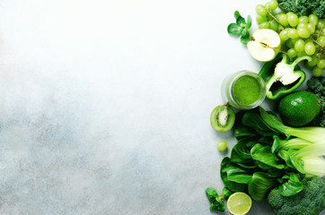 Green smoothie in glass jar with fresh organic green vegetables and fruits on grey background. Spring diet, healthy raw vegetarian, vegan concept, detox breakfast, alkaline clean eating. Copy space