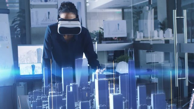 Professional Female Architect Wearing Makes Gestures with Augmented Reality Headset, Shows Statistics for 3D City Model. High Tech Office Use Virtual Reality Modeling Software Application.