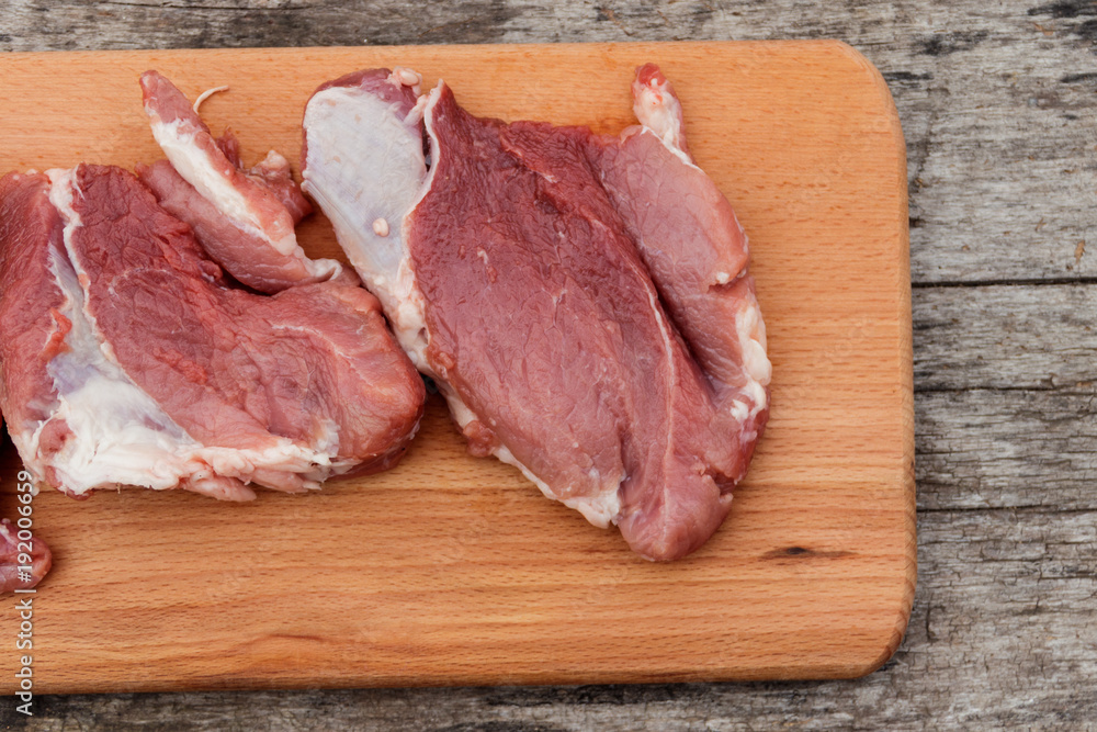 Wall mural raw pork meat on cutting board on a table. top view