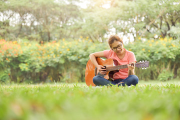 Female is sitting and playing Acoustic Guitar.