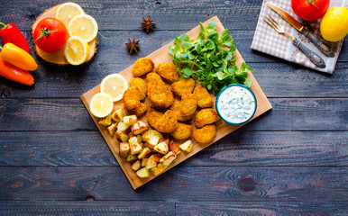 Chicken nuggets with yogurt sauce on a wooden background