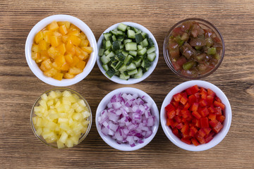 Assortment of colorful vegetables sliced, close up. Fresh peppers, tomatoes, cucumber and onion in bowls. Top view.