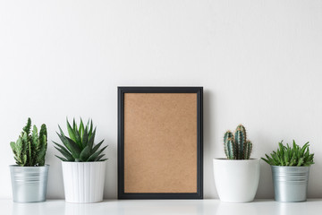 Modern room decoration. Various cactus and succulent plants in different pots. Mock-up with a black frame.