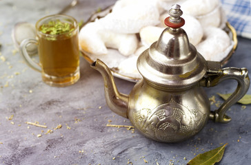 Oriental Algerian sweet cookies( kaab el ghazal), tea cup and pot  and mint leaves