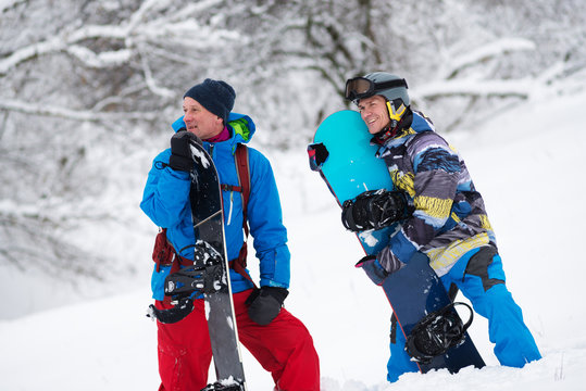 Two happy snowboarders relax after a successful descent