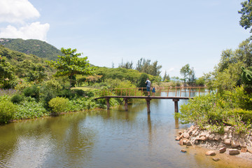 Happy father man with his little daughter walking across the wood sea bridge