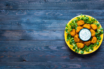 Chicken nuggets with yogurt sauce on a wooden background