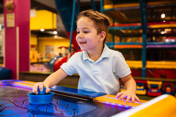 Happy little boy playing air hockey