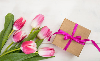 Women's day. Pink tulips and a gift on white background, top view