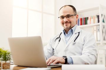 Portrait of doctor in glasses sitting at the desktop