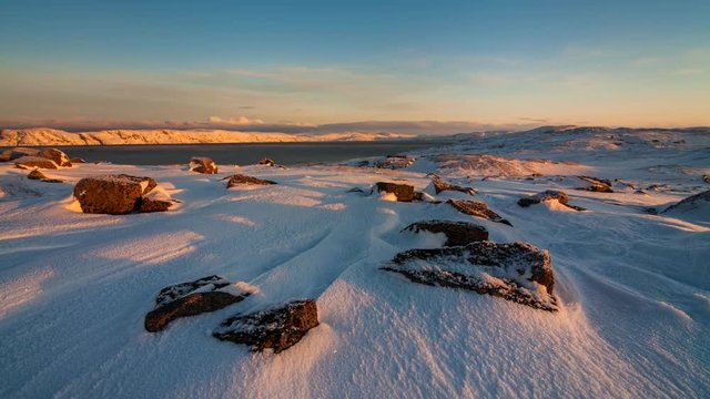 Sunset on the snow-covered shore of the Barents Sea