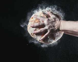 Fototapeta na wymiar Closeup of male hands put fresh bread on black background with copy space for your text