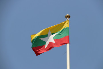 National flag of Myanmar on bright blue sky background. Blown away by wind. Myanmar is one of the ten Association of South East Asian Nations.