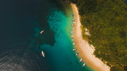 Beautiful beach with boats and tourists. Tropical bay in El Nido. Aerial view: bay and the tropical island. Tropical lagoon with turquoise water and white sand. Seascape: mountains, ocean. Sky and