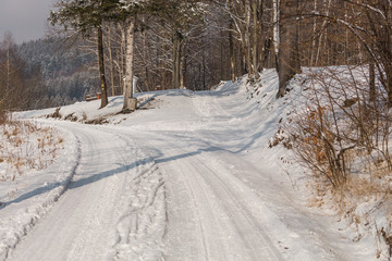 Empty snow covered road in winter landscape