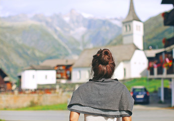 a girl in europe stands with her back, travel, Switzerland, view of the mountains and the old city, a woman travels and looks at the tower, the historic church