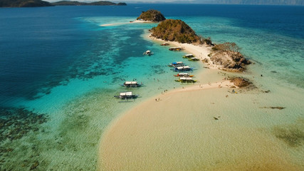Aerial view of tropical beach on the Bulog Dos Island, Philippines. Beautiful tropical island with sand beach, palm trees. Tropical landscape: beach with palm trees. Seascape: Ocean, sky, sea. Travel