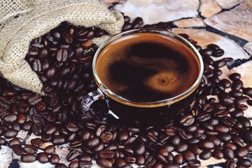 Cup of aromatic espresso with steam and coffee beans background. Cup of coffee isolated 