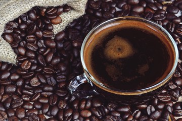 Cup of aromatic espresso with steam and coffee beans background. Cup of coffee isolated 