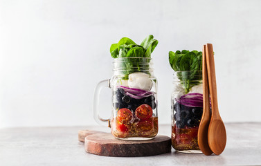 Mediterranean salad with cherry tomatoes, mozzarella cheese, black olives and onions in a glass jar. easy lunch or snack at work. healthy eating