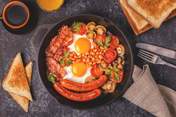 Traditional full English breakfast with fried eggs, sausages, beans, mushrooms, grilled tomatoes and bacon.