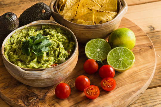 Guacamole dip in bowl with tortilla chips and ingredients