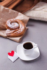 a cup of espresso on a saucer and a layered bun - a classic European or North American breakfast and a love letter in an envelope