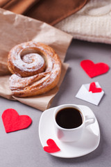 a cup of espresso on a saucer and a puff pastry, surrounded by hearts - a romantic breakfast on St. Valentine's Day