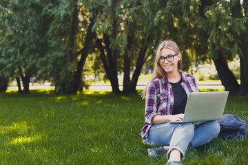 Happy young woman using laptop in park