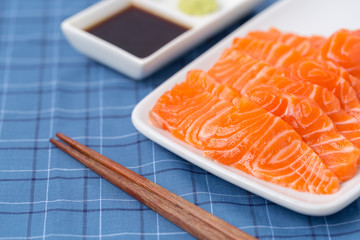 Salmon raw sashimi on whiteJapanese traditional dish on blue tablecloth.