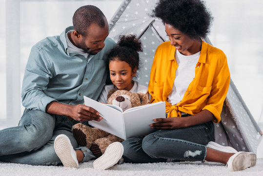 African American Parents Teaching Daughter To Read At Home