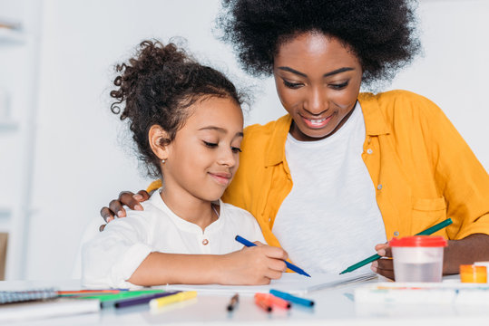 african american mother and daughter drawing together at home