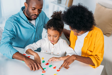african american parents teaching daughter mathematics at home