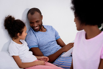 Fototapeta premium smiling african american parents and daughter looking at each other at home
