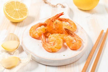 Fried shrimps with chopsticks on a white wooden board