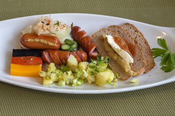 Three cheeses with the colors of the German flag, sandwich with  vegetables, wurst  and Bavarian mustard on a slice of bread, with mayonnaise, carrot cauliflower and potato salad.