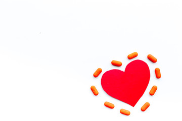 Vitamins of drugs for heart. Color pills near heart sign on white background top view copy space