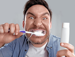 Handsome funny bearded man in whit shirt is obsessed about health of his teeth he cleaned them hard...