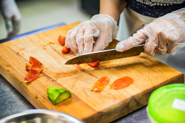 Hands in gloves cut vegetables