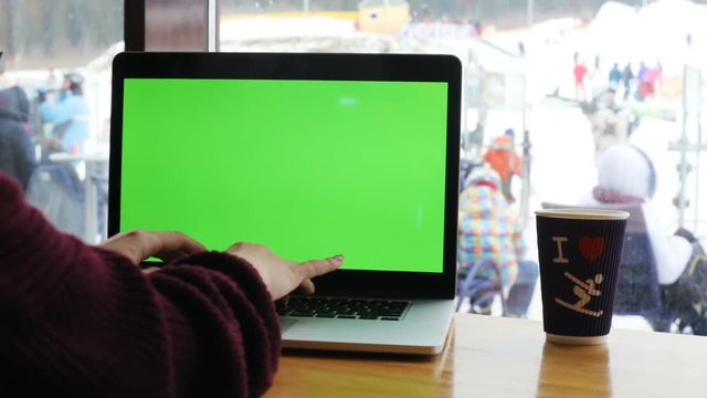 laptop girl sitting cafe window winter snow working online computer notebook freelancer programmer analyst closeup green screen display laptop keyboard typing cup coffee leisure rest active tourism