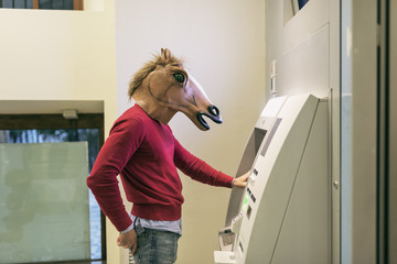attractive young horse man takes money from the ATM